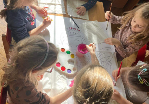 Dzieci malują farbami na dużym formacie.