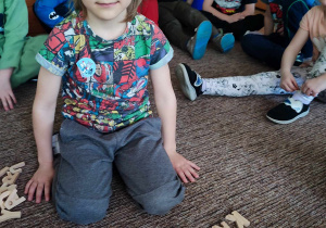 Chłopiec układa wyraz królik z drewnianych liter.